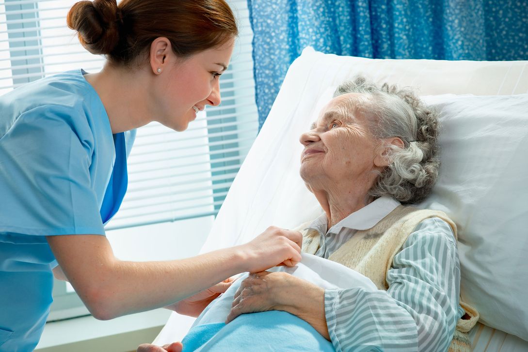 Nurse caring for elderly woman in a hospital bed